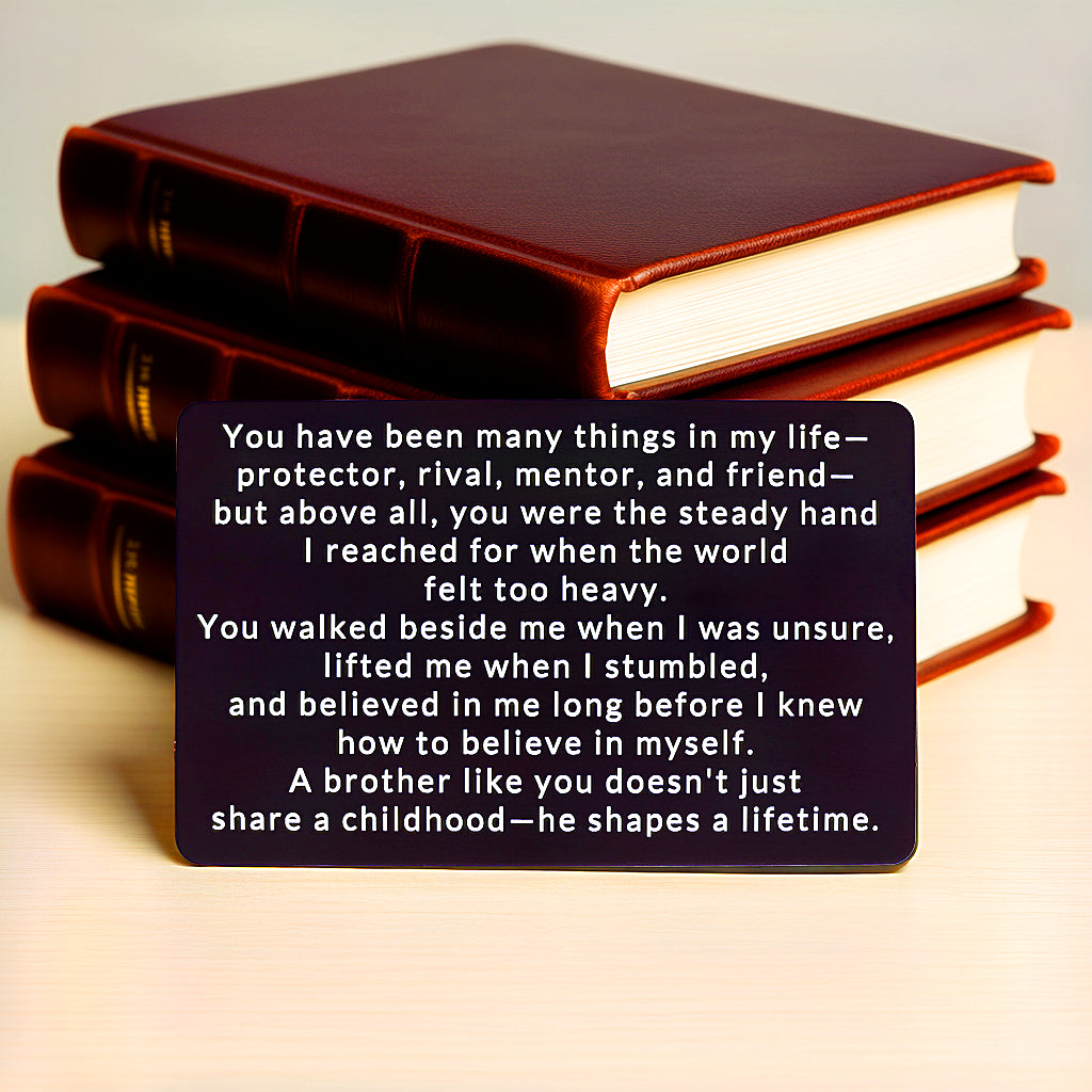 Black engraved metal wallet card reading 'A Brother Shapes A Lifetime' with three stacked brown leather-bound books in the background.