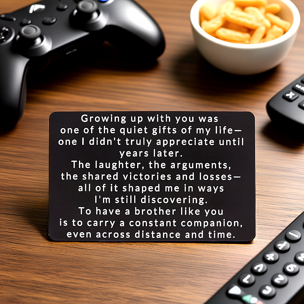 Black engraved metal wallet card reading 'Growing Up With You Was One Of The Quiet Gifts Of My Life' lying on a wooden table with a game controller, bowl of snacks, and two remotes in the background.